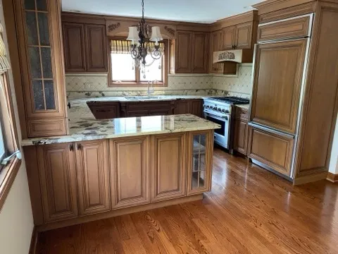 a kitchen with stainless steel appliances granite countertop a refrigerator a sink dishwasher a stove and white countertops with wooden floor