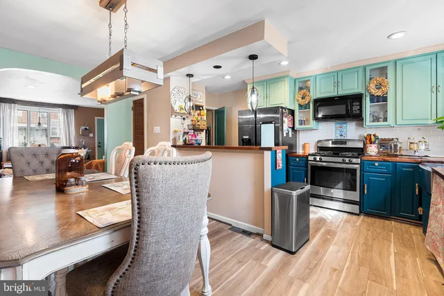 a kitchen with stainless steel appliances granite countertop a refrigerator a stove top oven a sink dishwasher and white cabinets with wooden floor