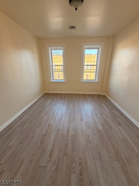 120 Bragaw Avenue, Unit 3 Newark, NJ 07112 - Photo 2 of 16 an empty room with wooden floor and windows
