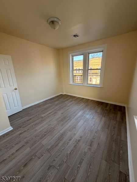 120 Bragaw Avenue, Unit 3 Newark, NJ 07112 - Photo 6 of 16 a view of an empty room with wooden floor and a window