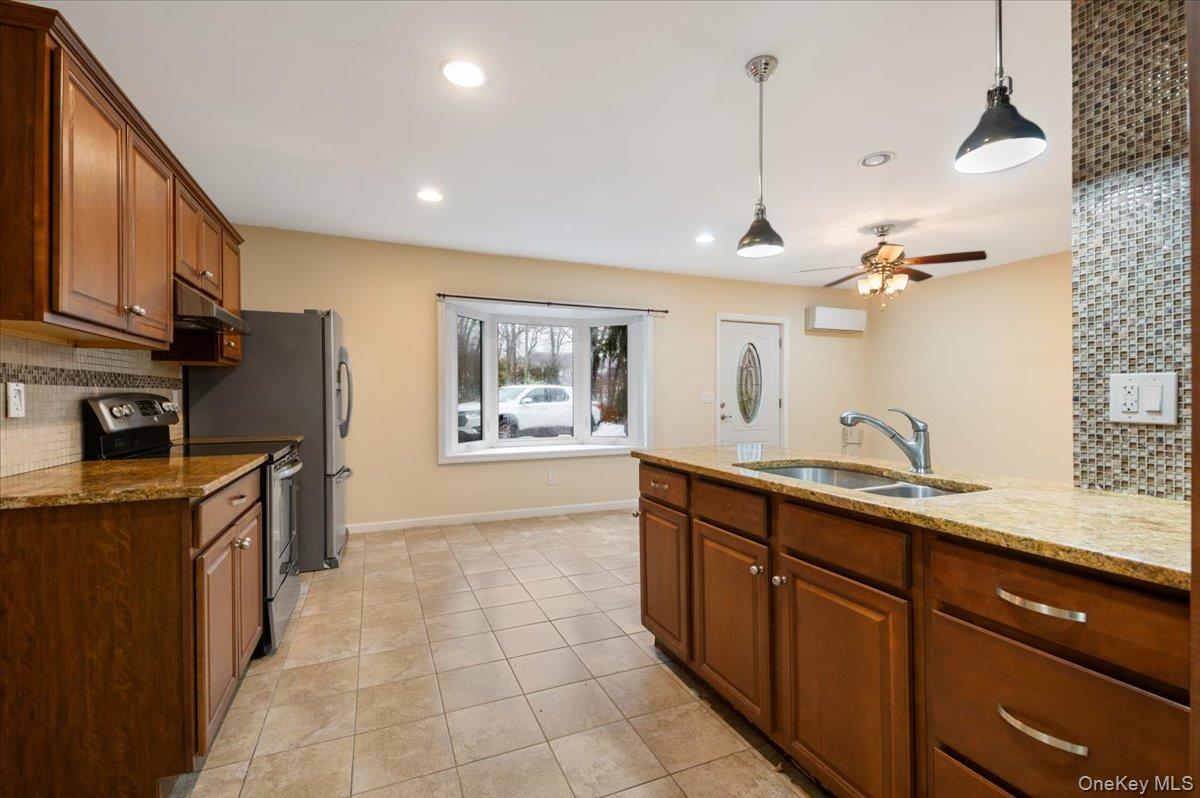 33 Fleets Cove Road Huntington, NY 11743 - Photo 29 of 42 Kitchen with decorative backsplash, brown cabinetry, stainless steel electric range, pendant lighting, and recessed lighting