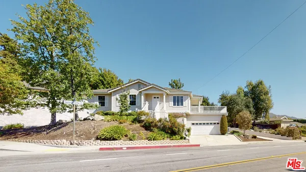 a view of a white house next to a road and yard