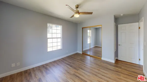 a view of empty room with wooden floor and fan