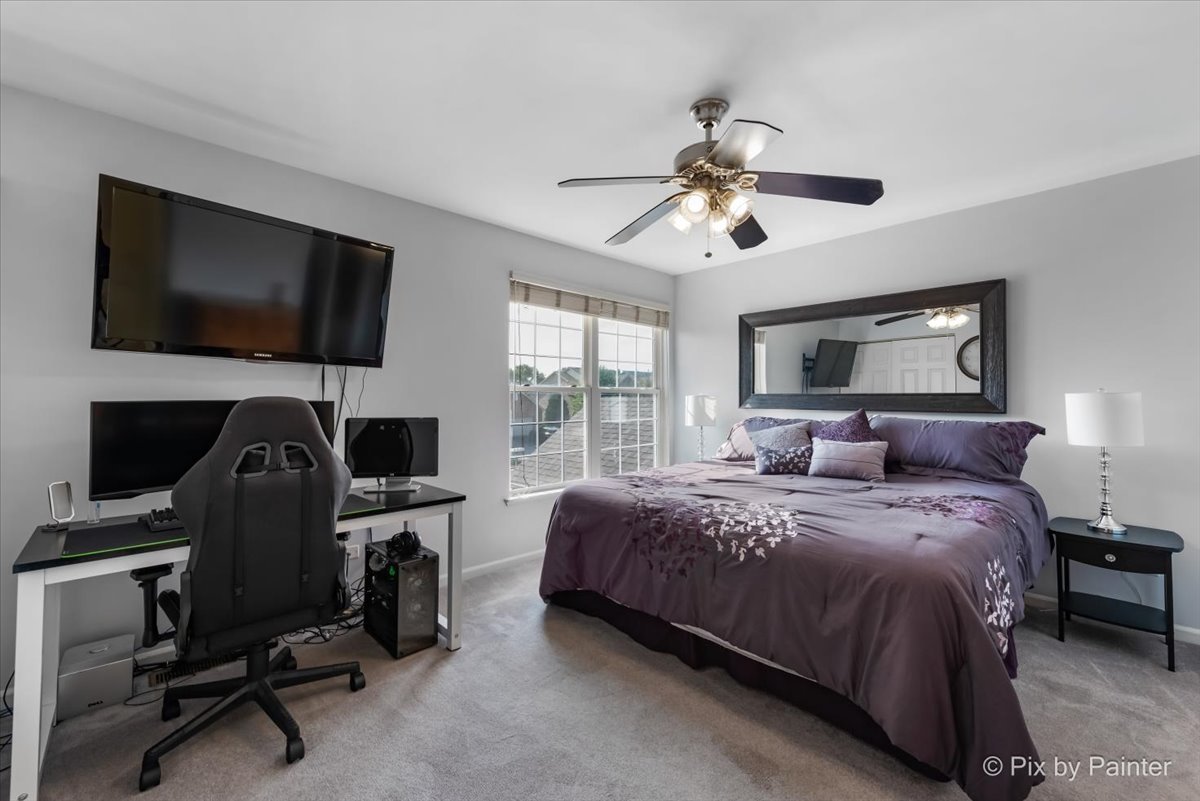 5742 Fieldstone Trail McHenry, IL 60050 - Photo 16 of 29 a bedroom with a bed a flat screen tv and a chandelier