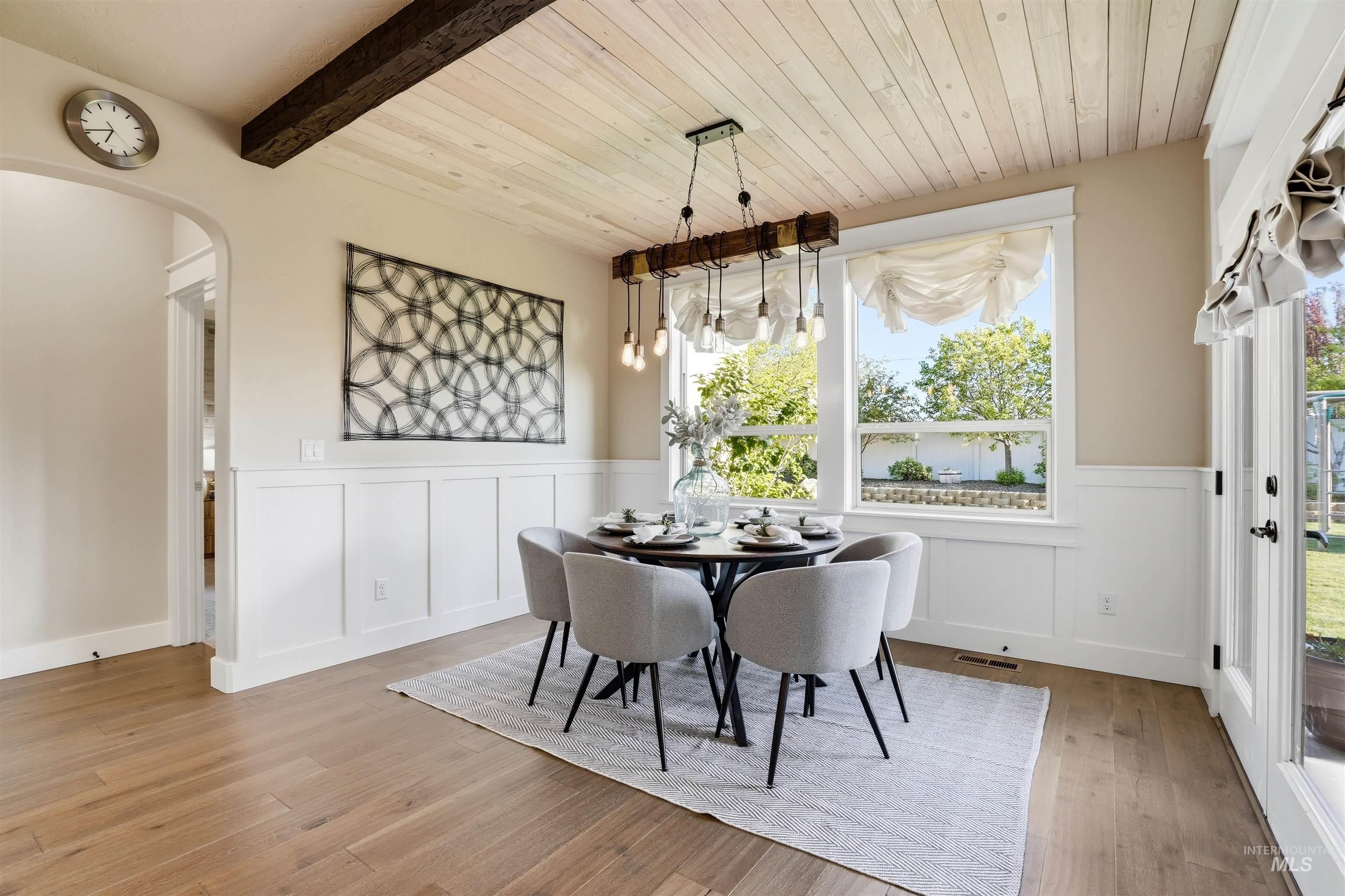 3915 West Riva Capri Street Meridian, ID 83646 - Photo 11 of 49 Dining area featuring wood-finish flooring, a wood-paneled ceiling with an exposed beam, and wainscoting