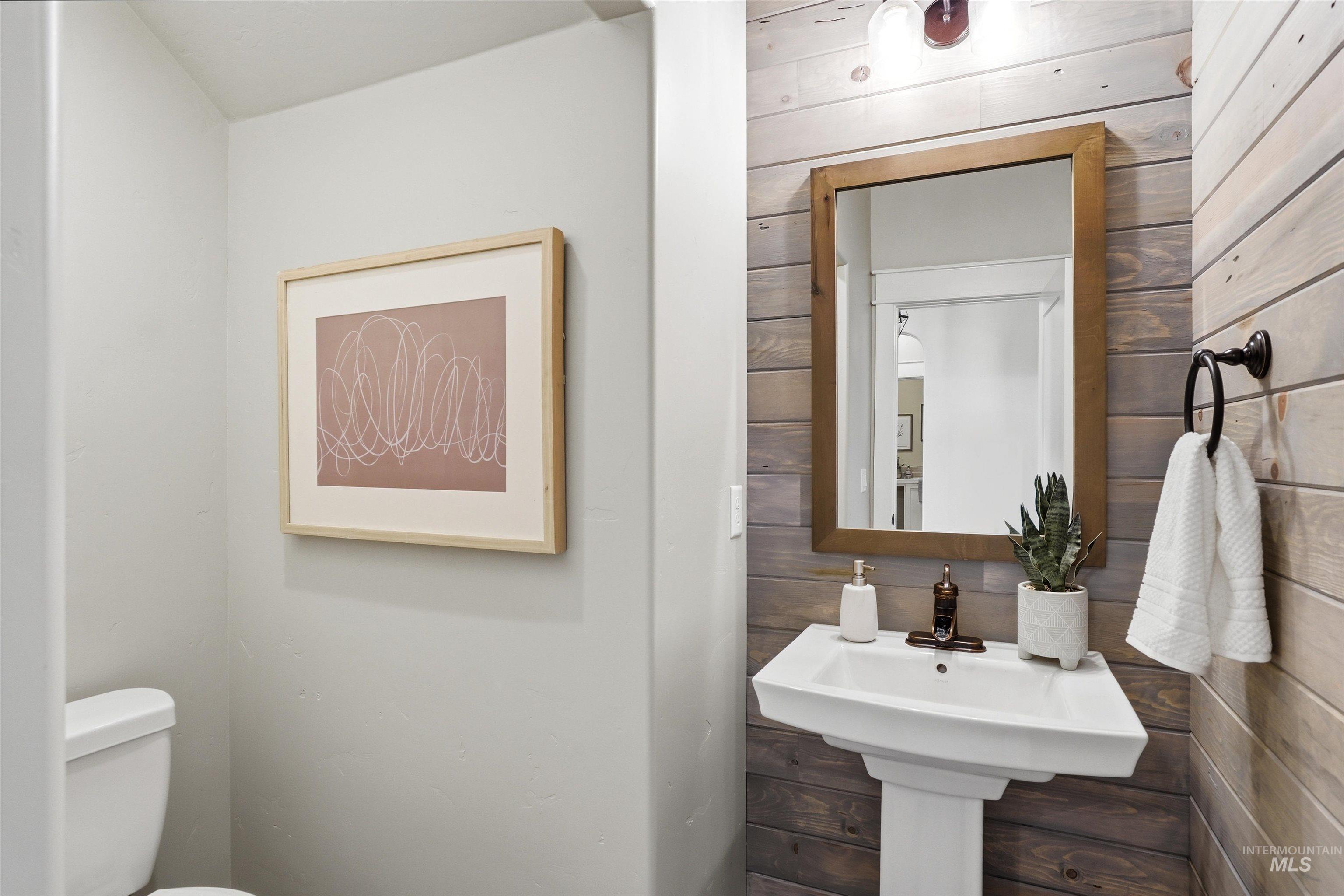 3915 West Riva Capri Street Meridian, ID 83646 - Photo 14 of 49 Pedestal sink with bronze faucet, framed mirror, and wood plank accent wall