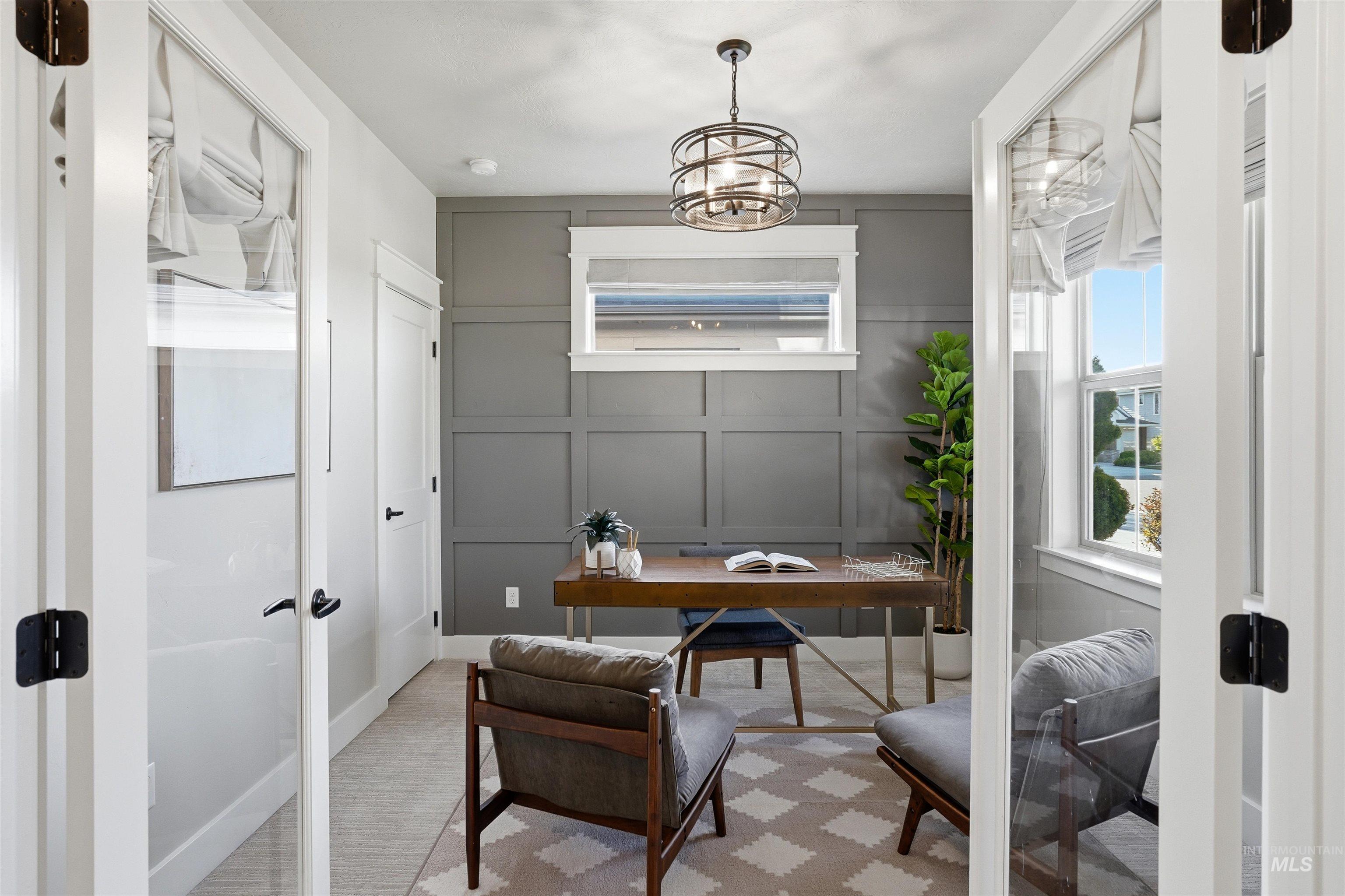3915 West Riva Capri Street Meridian, ID 83646 - Photo 15 of 49 French doors open to a room featuring decorative paneled walls, a single window with a privacy shade, and a contemporary caged chandelier