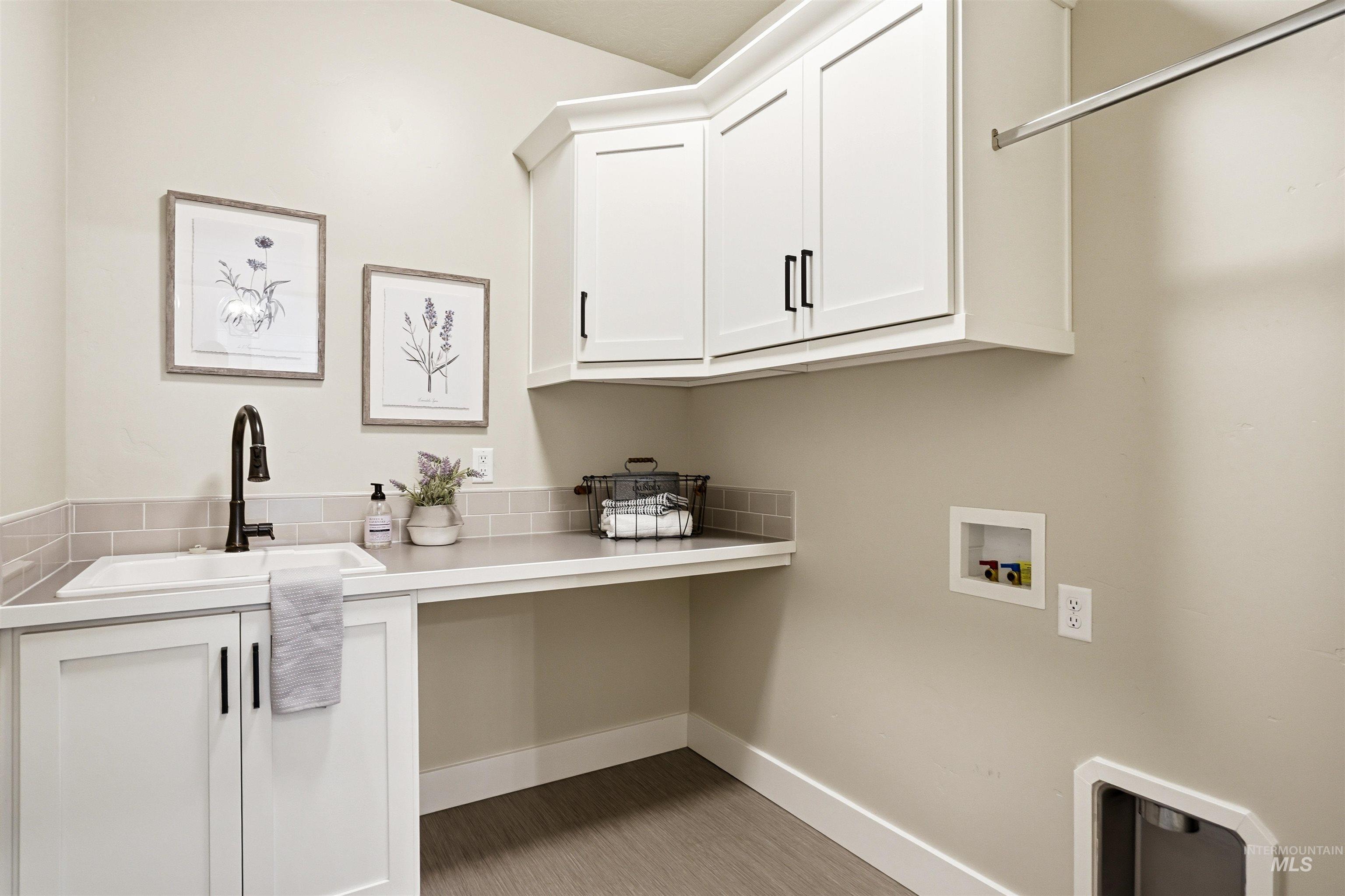 3915 West Riva Capri Street Meridian, ID 83646 - Photo 18 of 49 Utility room featuring white cabinetry, a built-in sink with a dark-finish faucet, an extended countertop, and light-toned flooring