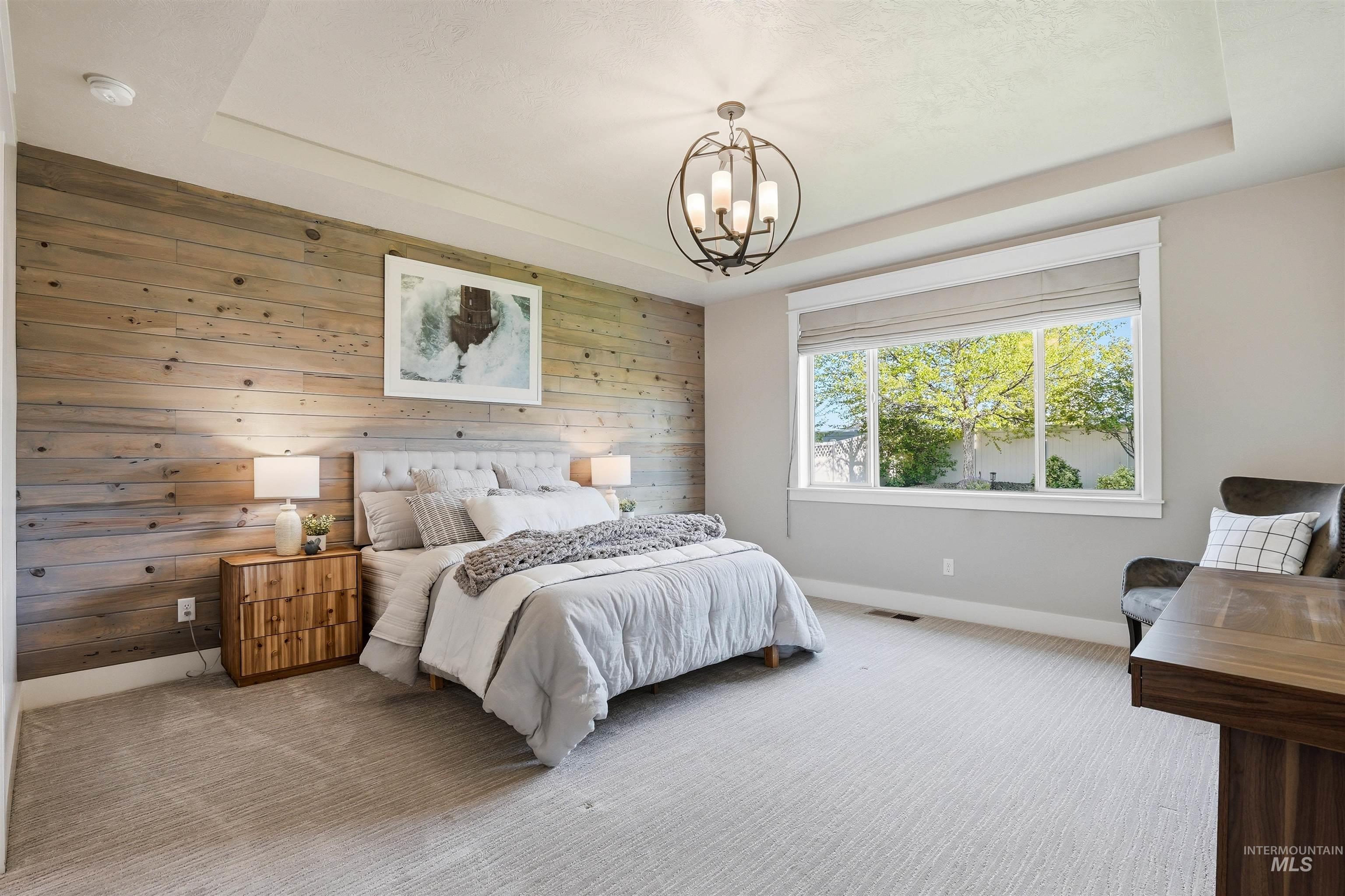 3915 West Riva Capri Street Meridian, ID 83646 - Photo 19 of 49 Spacious room featuring a wood-panel accent wall, tray ceiling, and a large window with privacy blinds