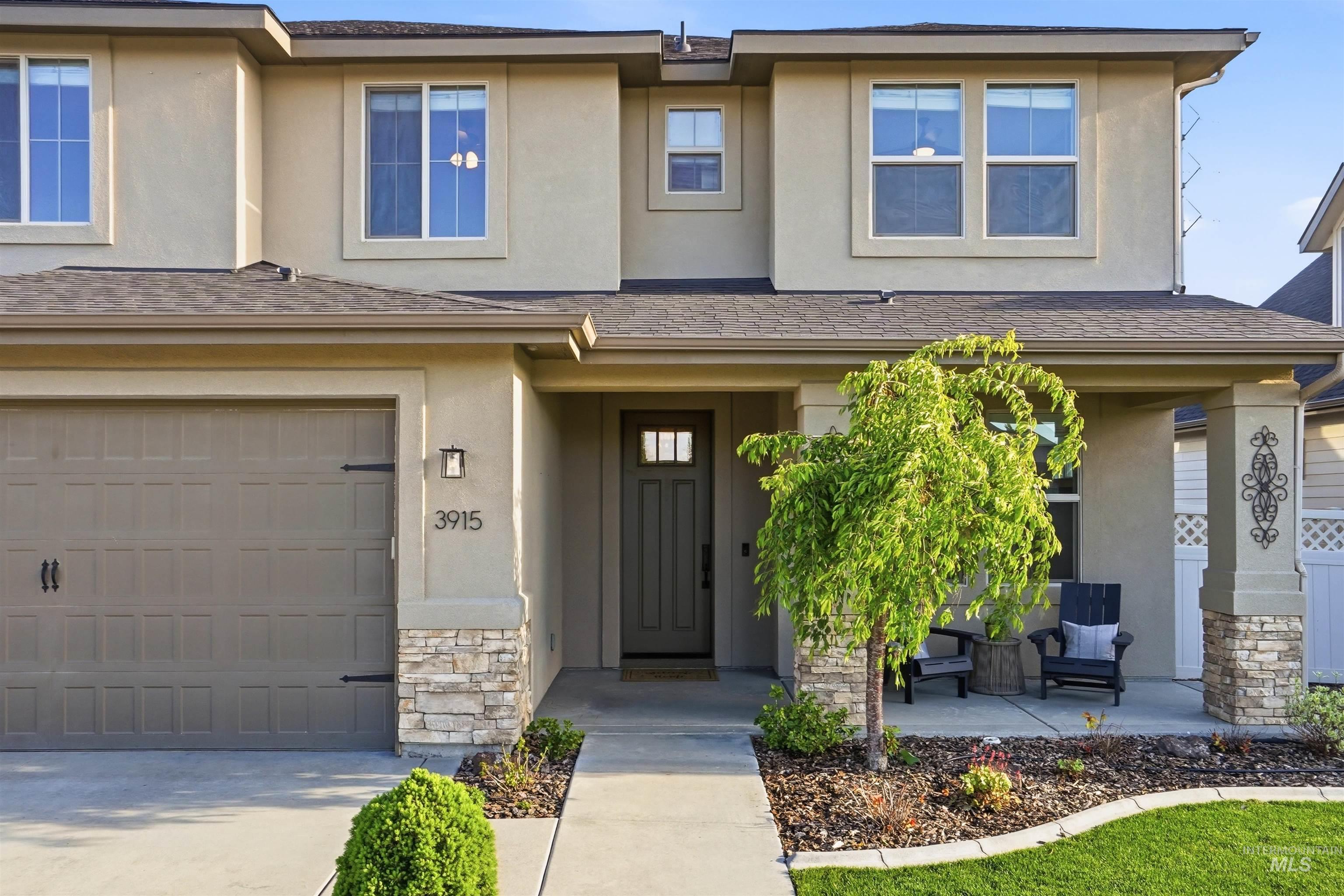 3915 West Riva Capri Street Meridian, ID 83646 - Photo 2 of 49 Contemporary stucco facade featuring a covered entry, stone veneer accents, an attached garage, and landscaping