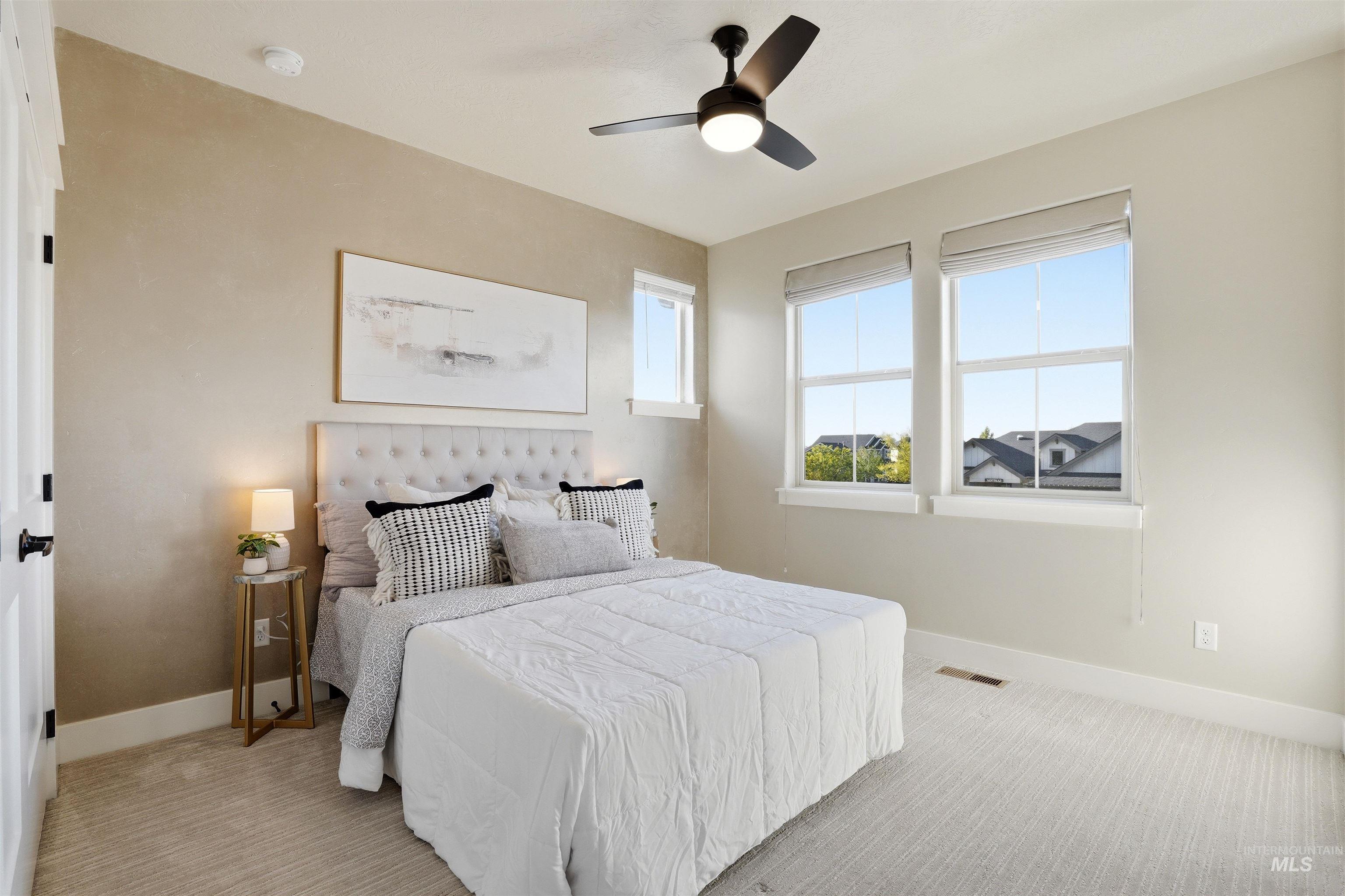 3915 West Riva Capri Street Meridian, ID 83646 - Photo 25 of 49 Carpeted room featuring a ceiling fan with light, three windows with roller shades, and a white paneled door with black hardware