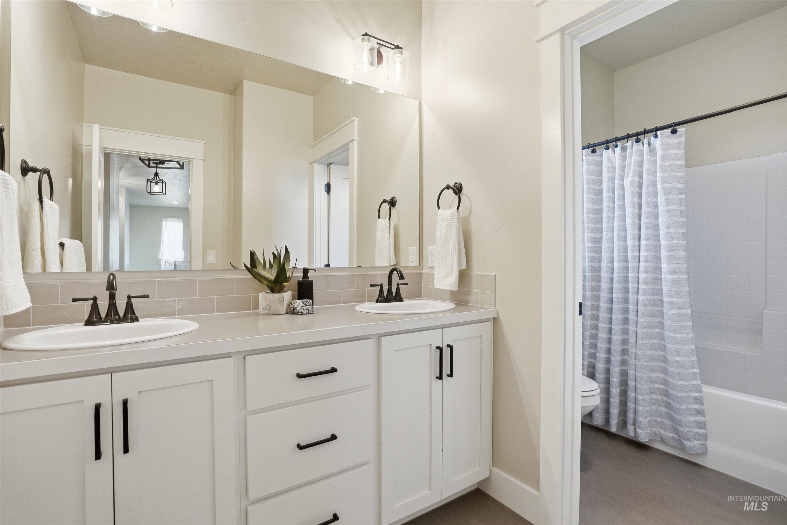 3915 West Riva Capri Street Meridian, ID 83646 - Photo 27 of 49 Dual vanity with white cabinetry and dark hardware, featuring integrated sinks and a light-colored countertop
