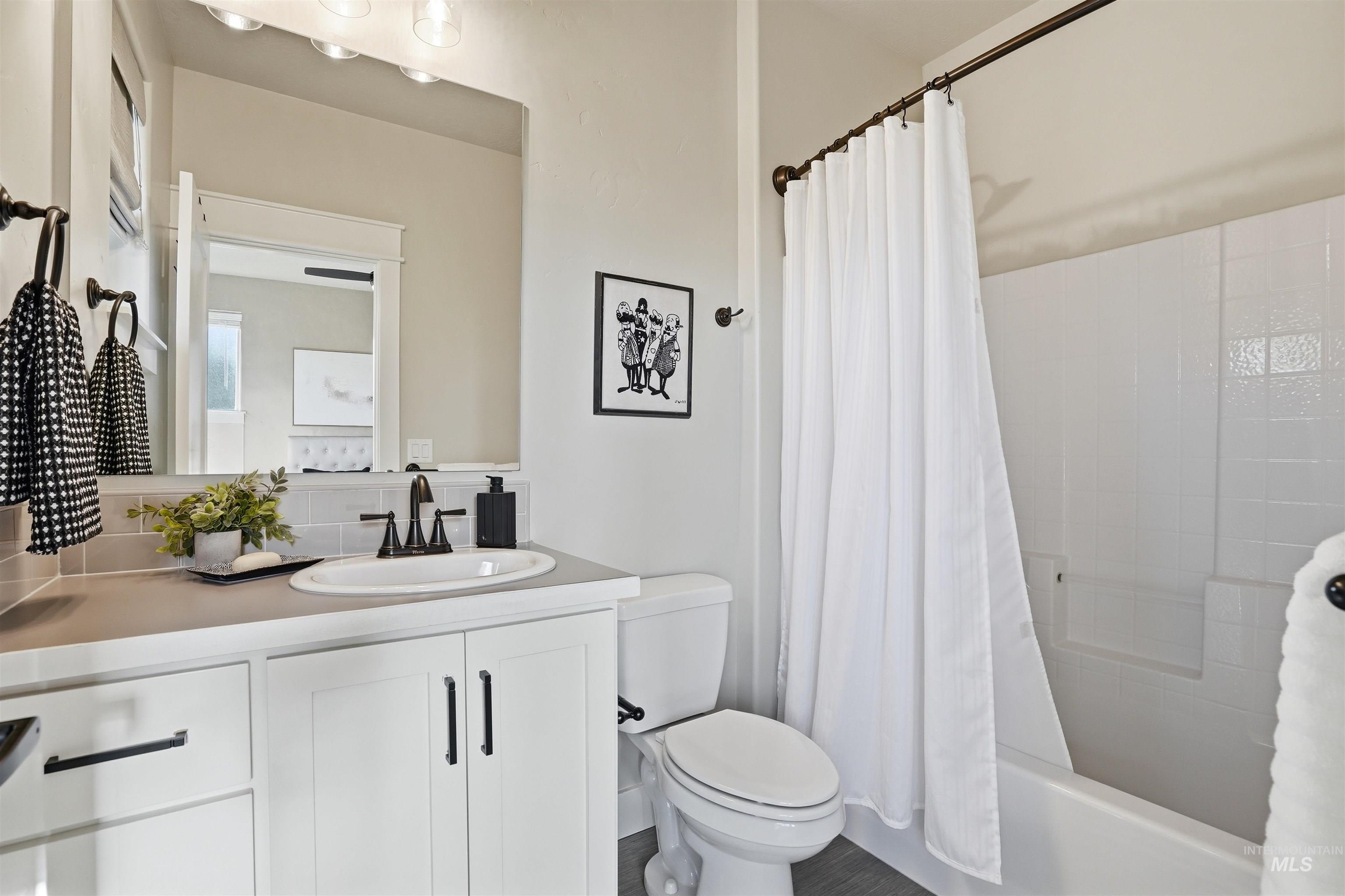 3915 West Riva Capri Street Meridian, ID 83646 - Photo 30 of 49 Bathroom featuring a white vanity with integrated sink, dark bronze fixtures, and a subway tile backsplash