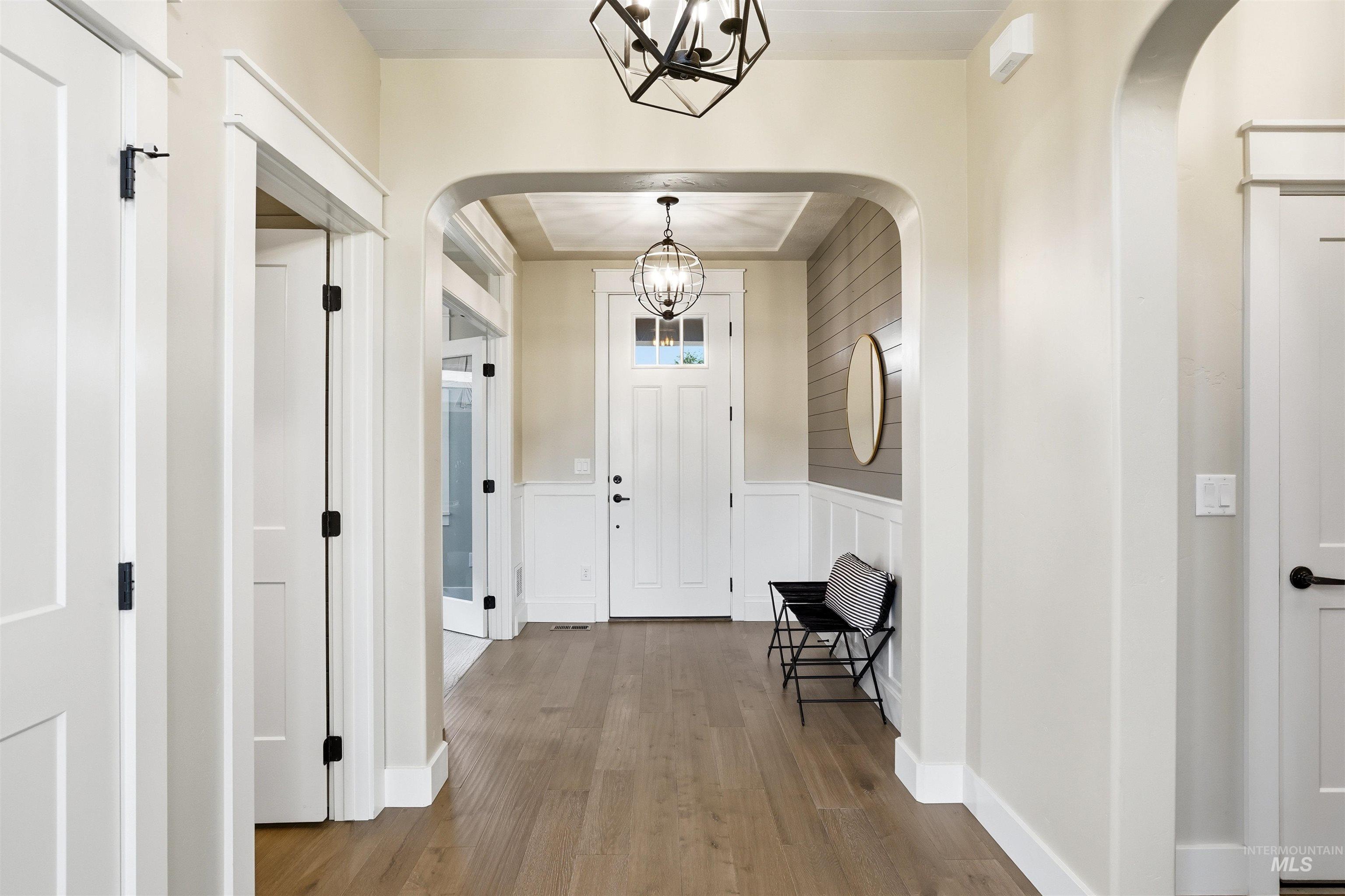 3915 West Riva Capri Street Meridian, ID 83646 - Photo 3 of 49 Entryway featuring wood-finish flooring, wainscoting, and an arched doorway