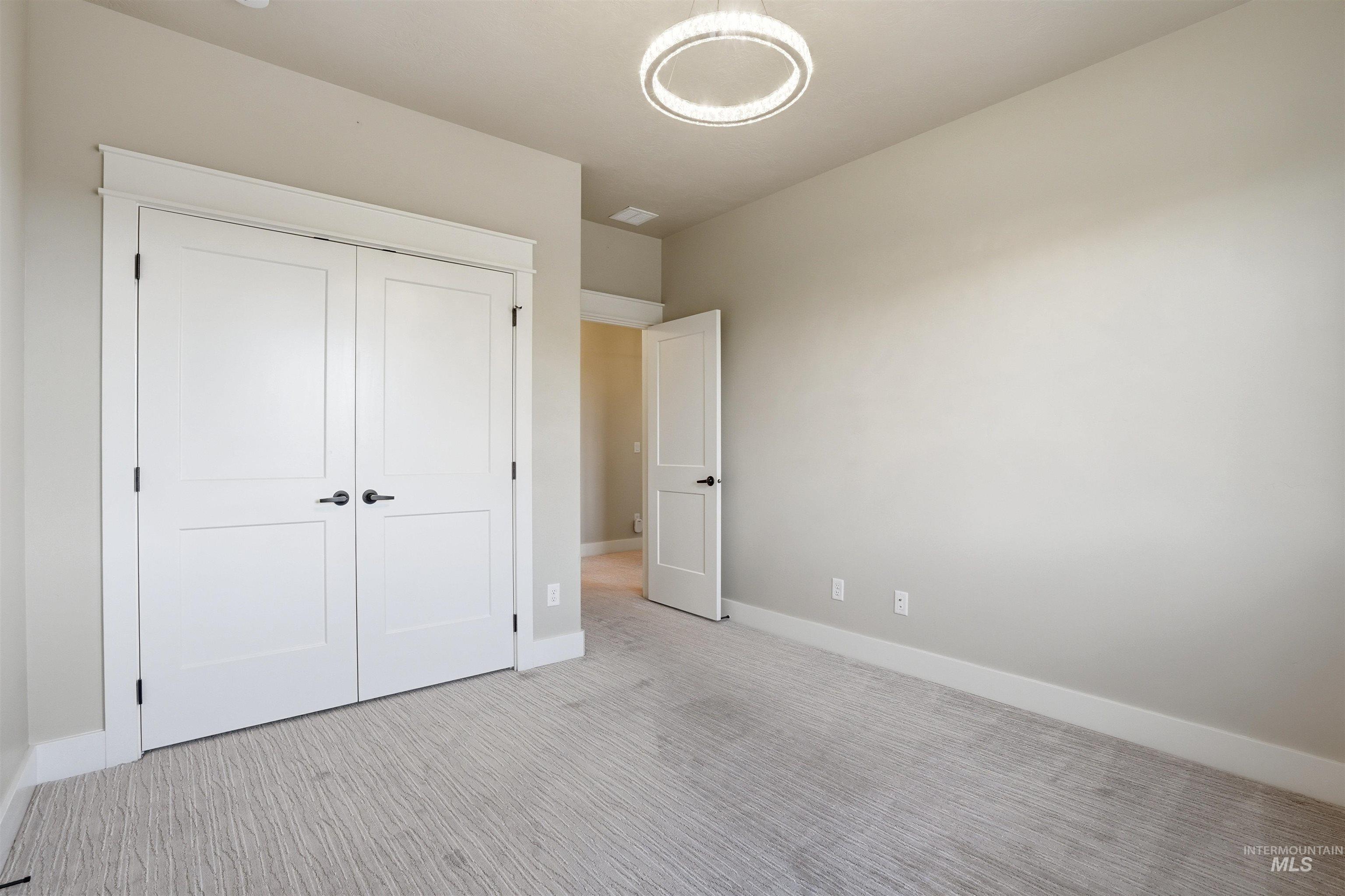 3915 West Riva Capri Street Meridian, ID 83646 - Photo 33 of 49 Spacious room featuring light gray walls, textured gray carpeting, white baseboards, and white two-panel bi-fold closet doors with black hardware