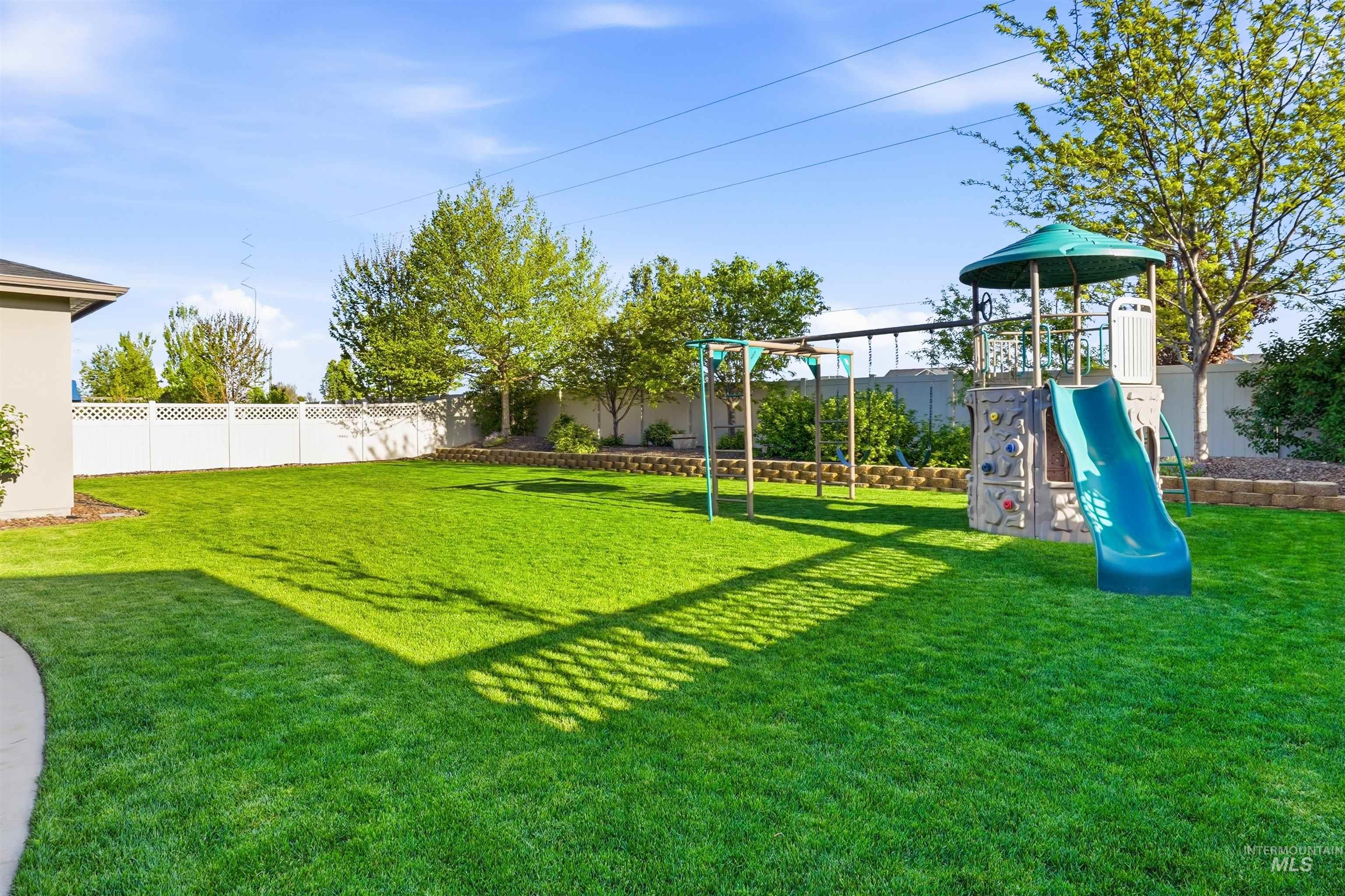 3915 West Riva Capri Street Meridian, ID 83646 - Photo 34 of 49 Expansive lawn area featuring a decorative white lattice fence and mature trees