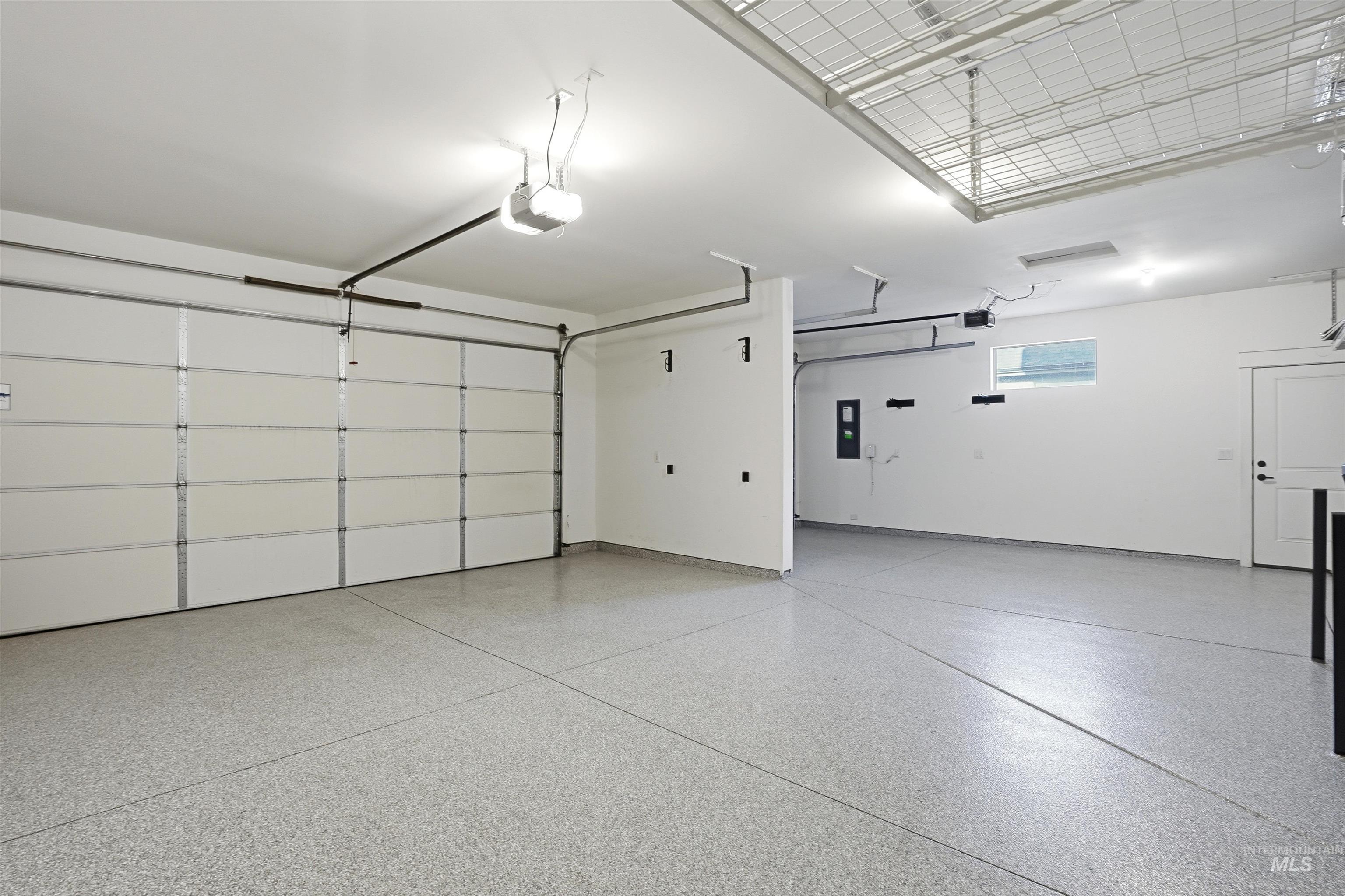 3915 West Riva Capri Street Meridian, ID 83646 - Photo 41 of 49 Spacious garage featuring a light-toned epoxy floor finish, automatic garage door opener, overhead lighting, and a transom window