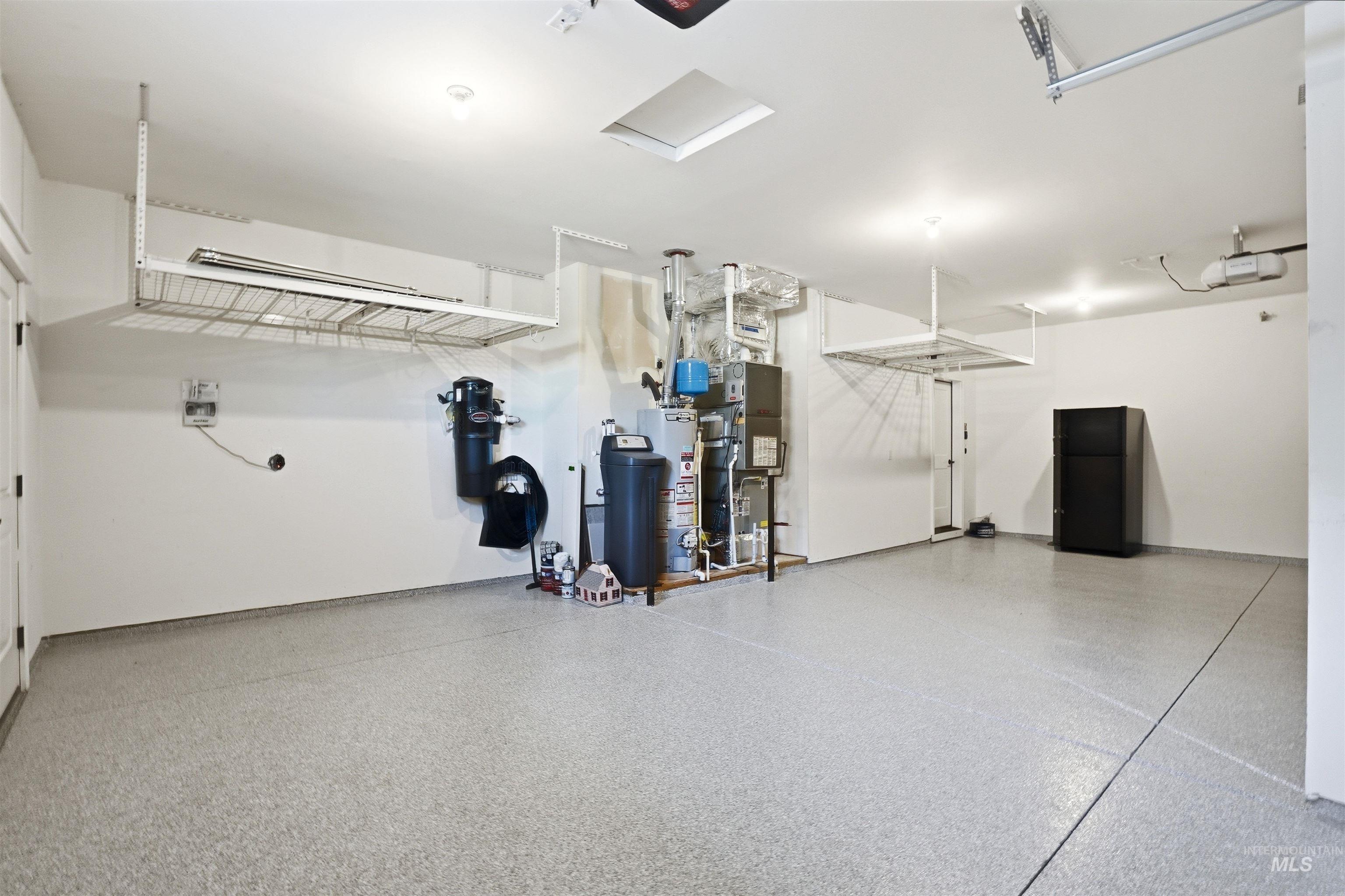 3915 West Riva Capri Street Meridian, ID 83646 - Photo 42 of 49 Spacious garage featuring a light-colored epoxy floor, overhead storage racks, recessed lighting, and a skylight