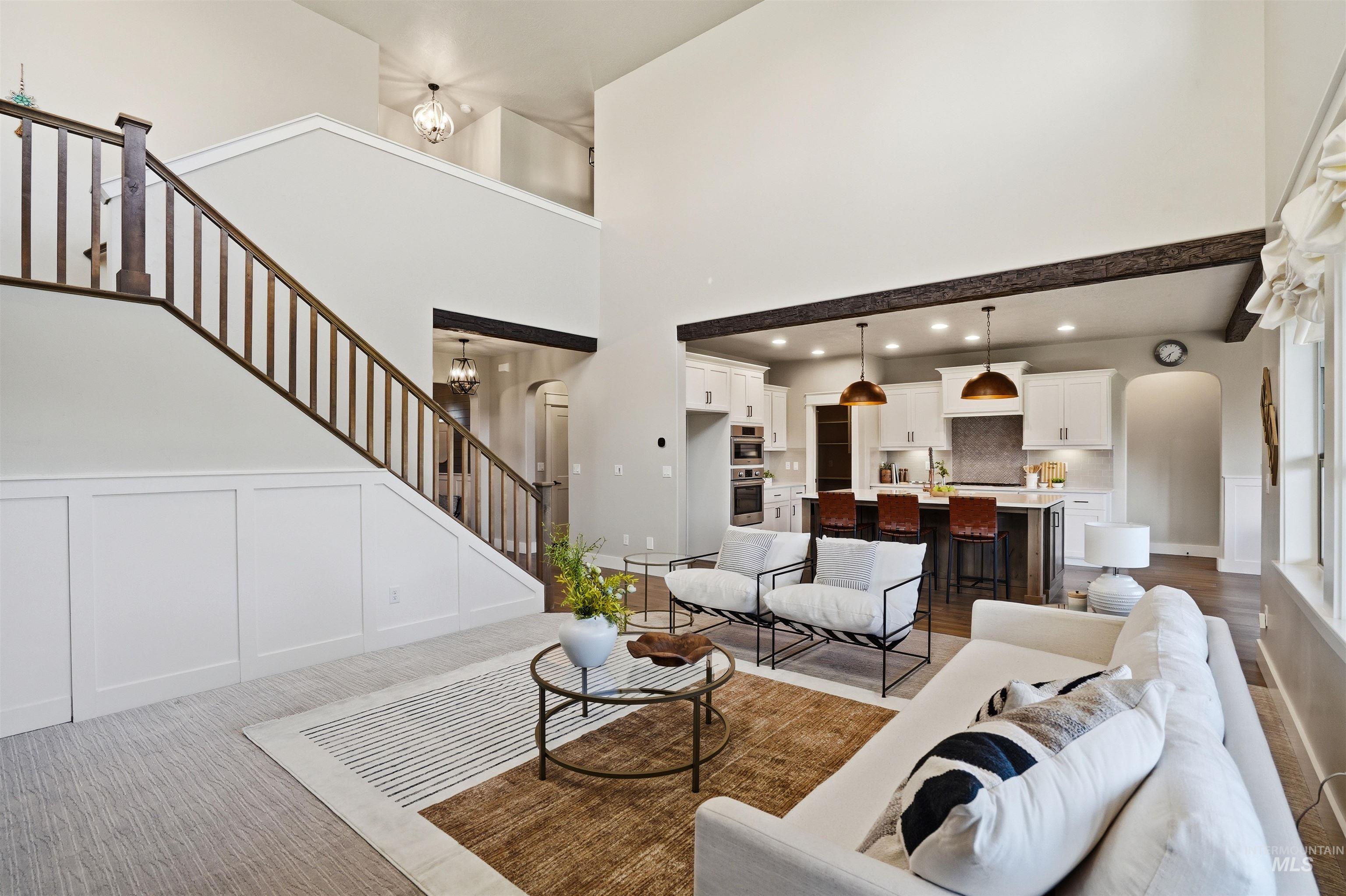 3915 West Riva Capri Street Meridian, ID 83646 - Photo 5 of 49 Two-story living area featuring a prominent staircase with wood newel posts and balusters, wainscoting, and wood-finish flooring