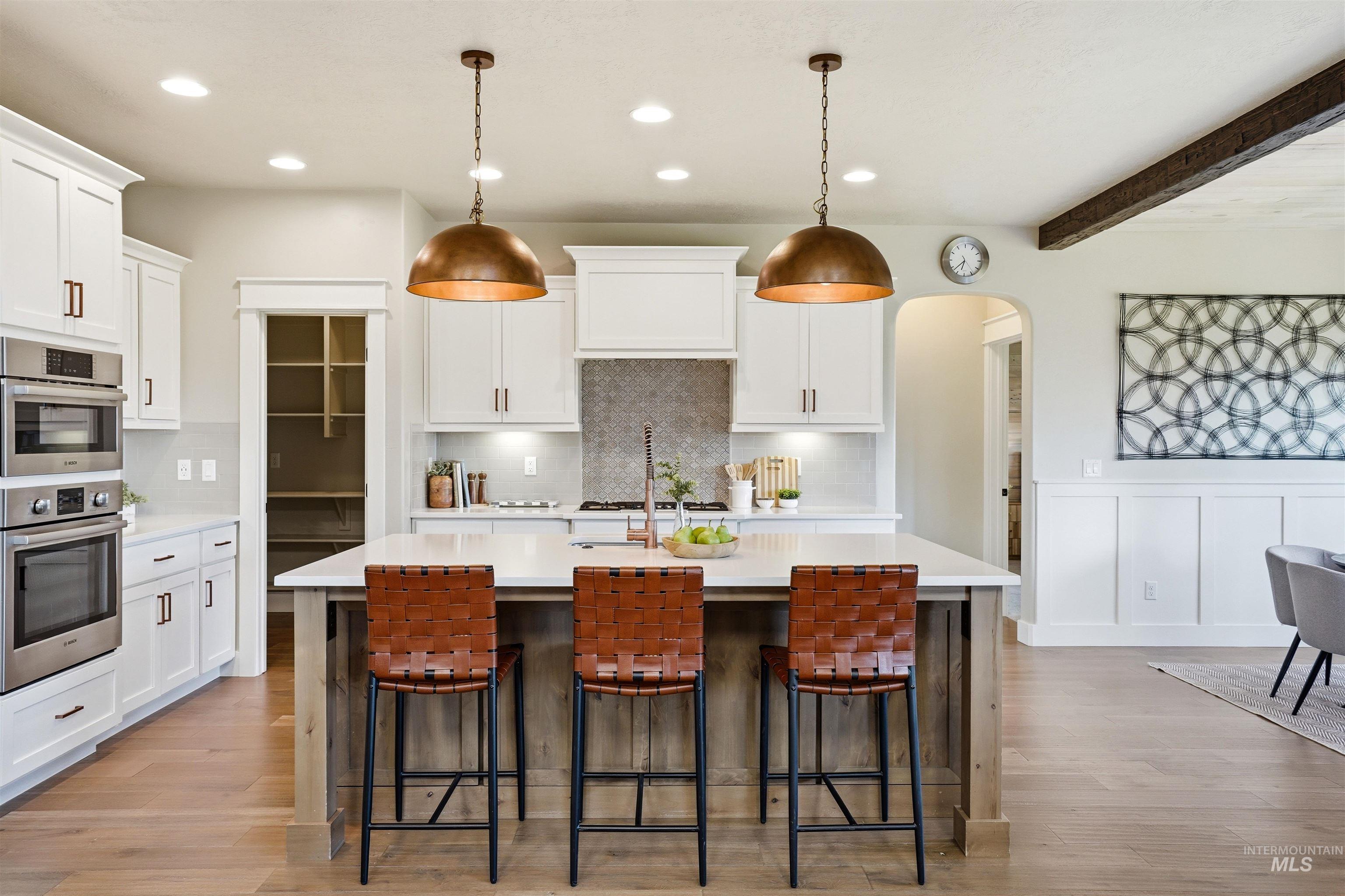 3915 West Riva Capri Street Meridian, ID 83646 - Photo 6 of 49 Expansive kitchen featuring a large central island with seating, white shaker cabinetry, stainless steel double ovens, a recessed pantry, and light wood-finish flooring