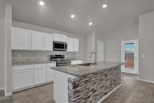 a kitchen with granite countertop a sink and white cabinets