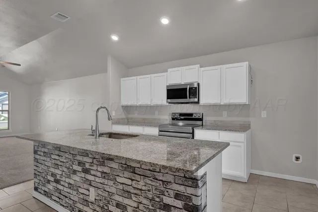 a kitchen with stainless steel appliances granite countertop a sink stove and microwave