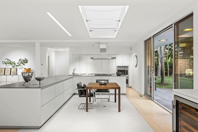 a kitchen with sink stove and white cabinets with wooden floor