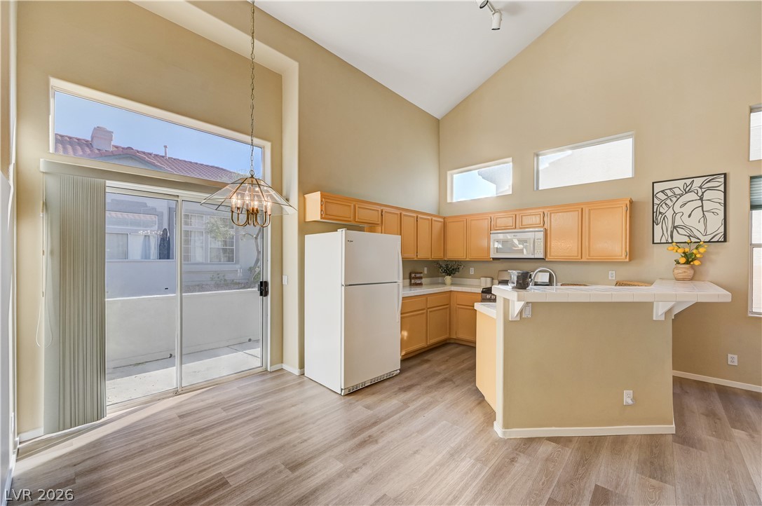 High vaulted ceilings and rich wood-style flooring elevate this bright dining and kitchen space.