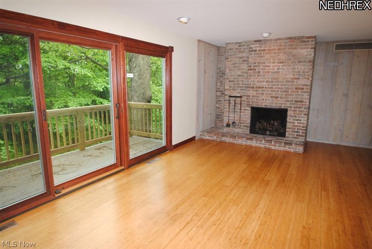 4846 Ranchwood Road Akron, OH 44333 - Photo 7 of 23 The living room features a floor to ceiling fireplace with handmade bricks from an 1800's farmhouse. Newer sliding doors open to a balcony overlooking the expansive view of nature.