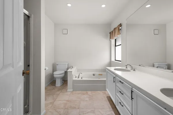a spacious bathroom with a bathtub sink mirror and toilet