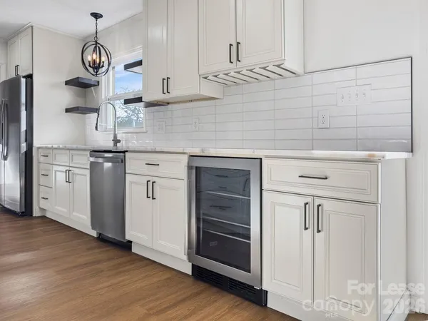 a kitchen with stainless steel appliances granite countertop a sink a stove and white cabinets