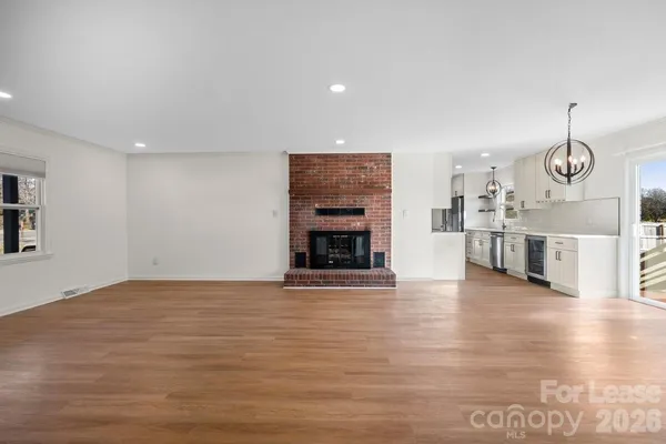 a view of an empty room with wooden floor and fireplace