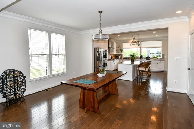 a kitchen with stainless steel appliances a dining table chairs refrigerator and sink