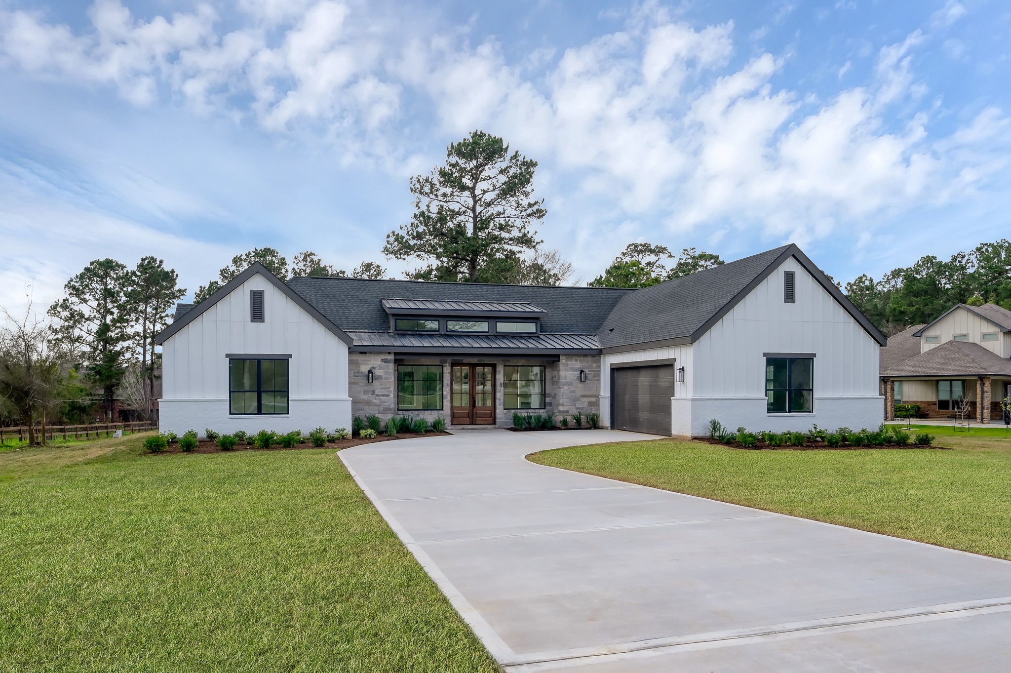 14742 Turquoise Trail Willis, TX 77378 - Photo 44 of 48 Stunning custom modern farmhouse situated on a spacious 1.04-acre lot with clean architectural lines, board-and-batten exterior, and stone accents. The long concrete drive and lush landscaping create a welcoming first impression.