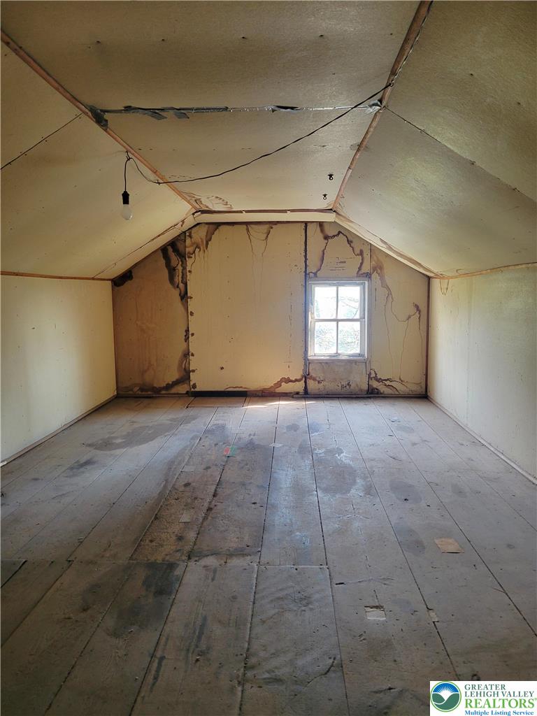 3913 Lime Kiln Road Allentown, PA 18104 - Photo 31 of 38 An attic space awaits transformation, featuring rustic wood flooring and a lone window.