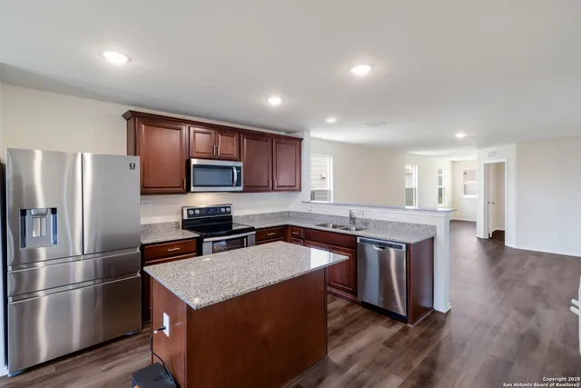 a kitchen with stainless steel appliances granite countertop a stove a sink a refrigerator and a microwave