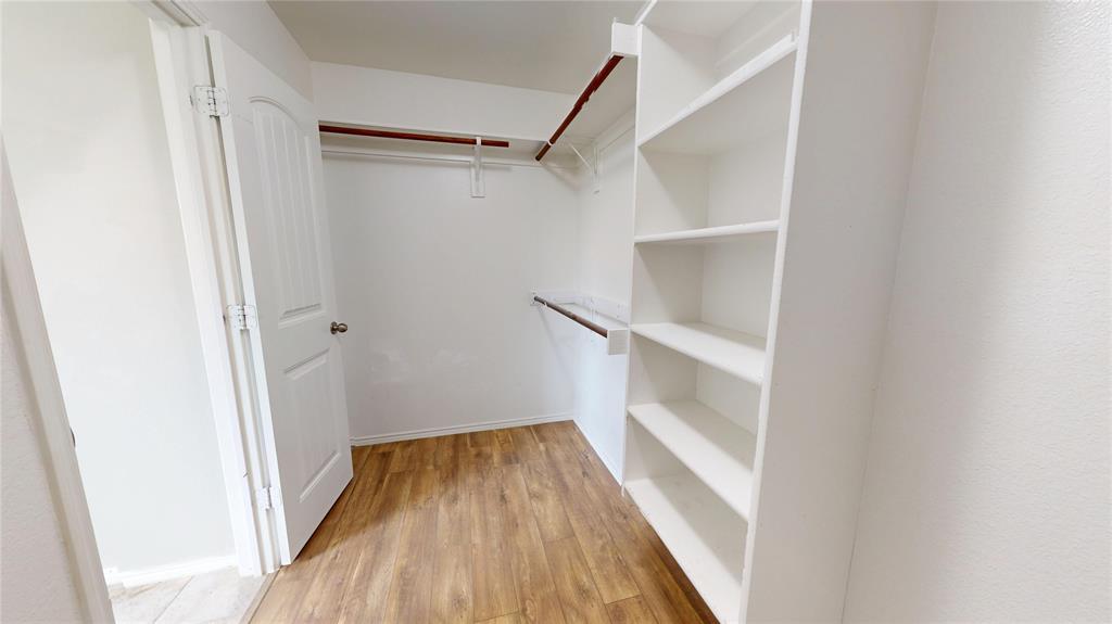 3101 Buckthorn Street Forney, TX 75126 - Photo 21 of 40 Walk-in closet featuring wood-finish flooring, built-in shelving, and multiple hanging rods