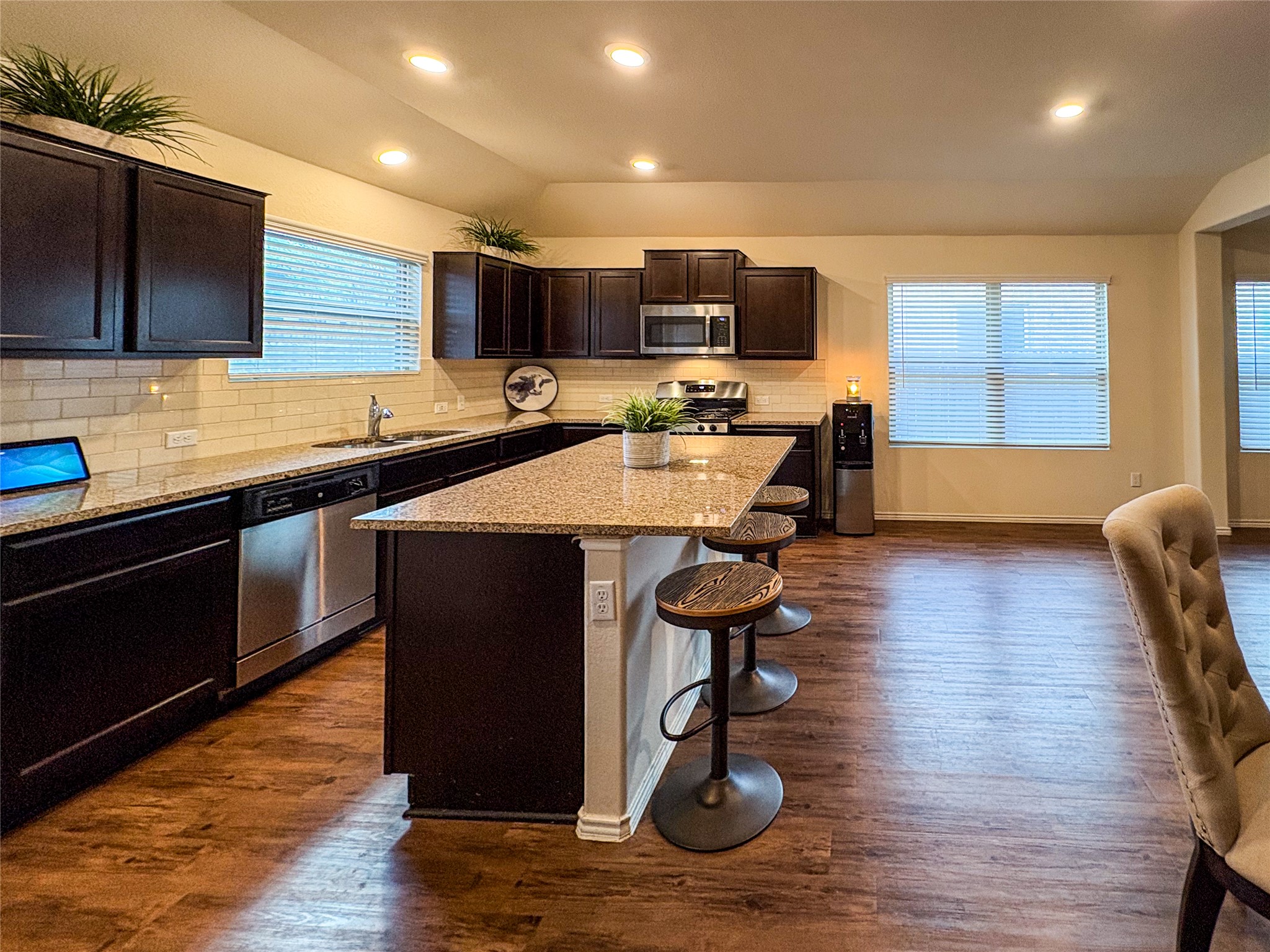 307 Andesite Trail Buda, TX 78610 - Photo 6 of 19 a kitchen with stainless steel appliances granite countertop a sink dishwasher a stove with wooden cabinets and floor
