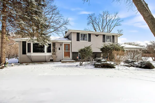 a front view of a house with a yard covered in snow