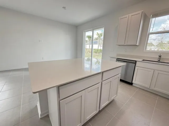 a kitchen with white cabinets and window