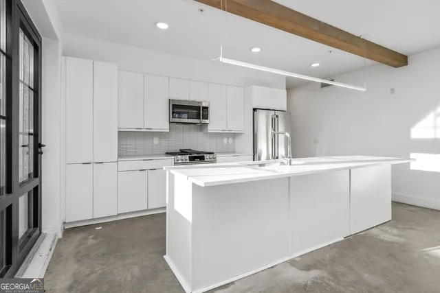 a kitchen with kitchen island white cabinets and refrigerator