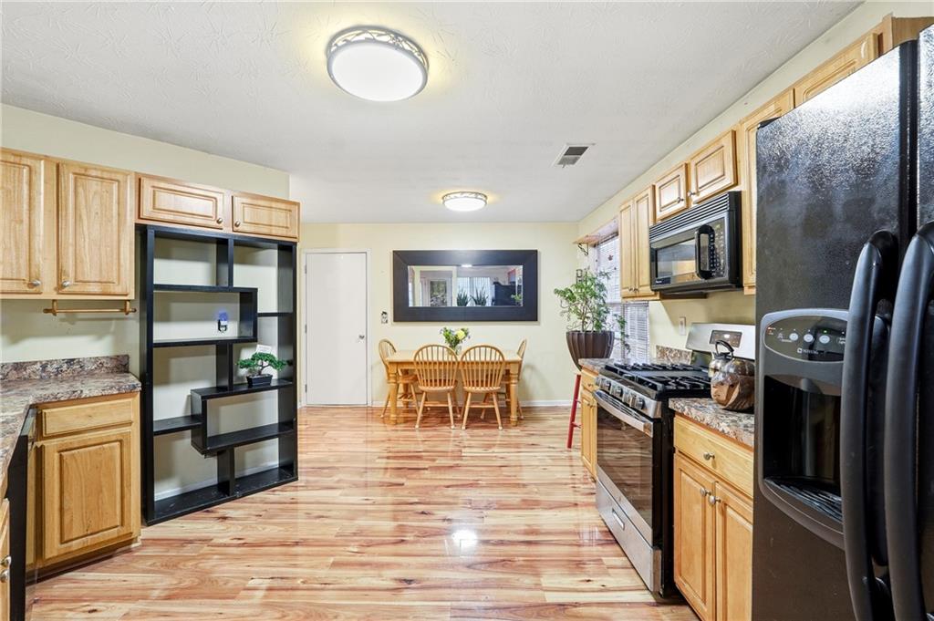 20 Ivans Circle Covington, GA 30016 - Photo 13 of 29 a kitchen with stainless steel appliances granite countertop a stove top oven a sink dishwasher a dining table and chairs with wooden floor