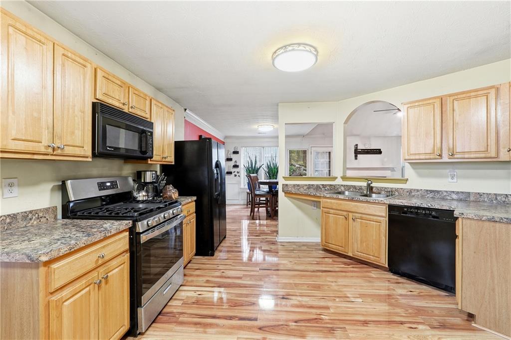 20 Ivans Circle Covington, GA 30016 - Photo 15 of 29 a kitchen with stainless steel appliances granite countertop a stove top oven a sink dishwasher a dining table and chairs with wooden floor
