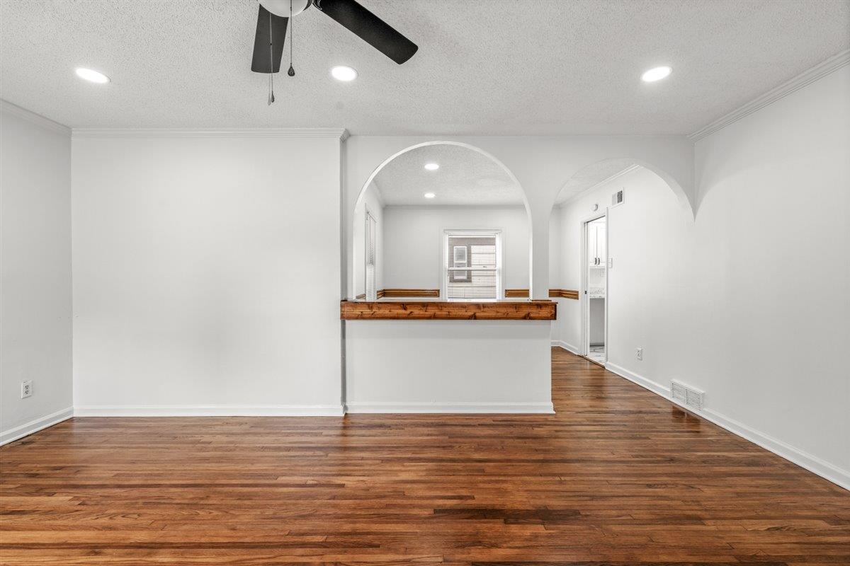 1244 Wells Station Road Memphis, TN 38122 - Photo 8 of 36 Unfurnished living room featuring a ceiling fan, a textured ceiling, dark wood-style floors, recessed lighting, and arched walkways