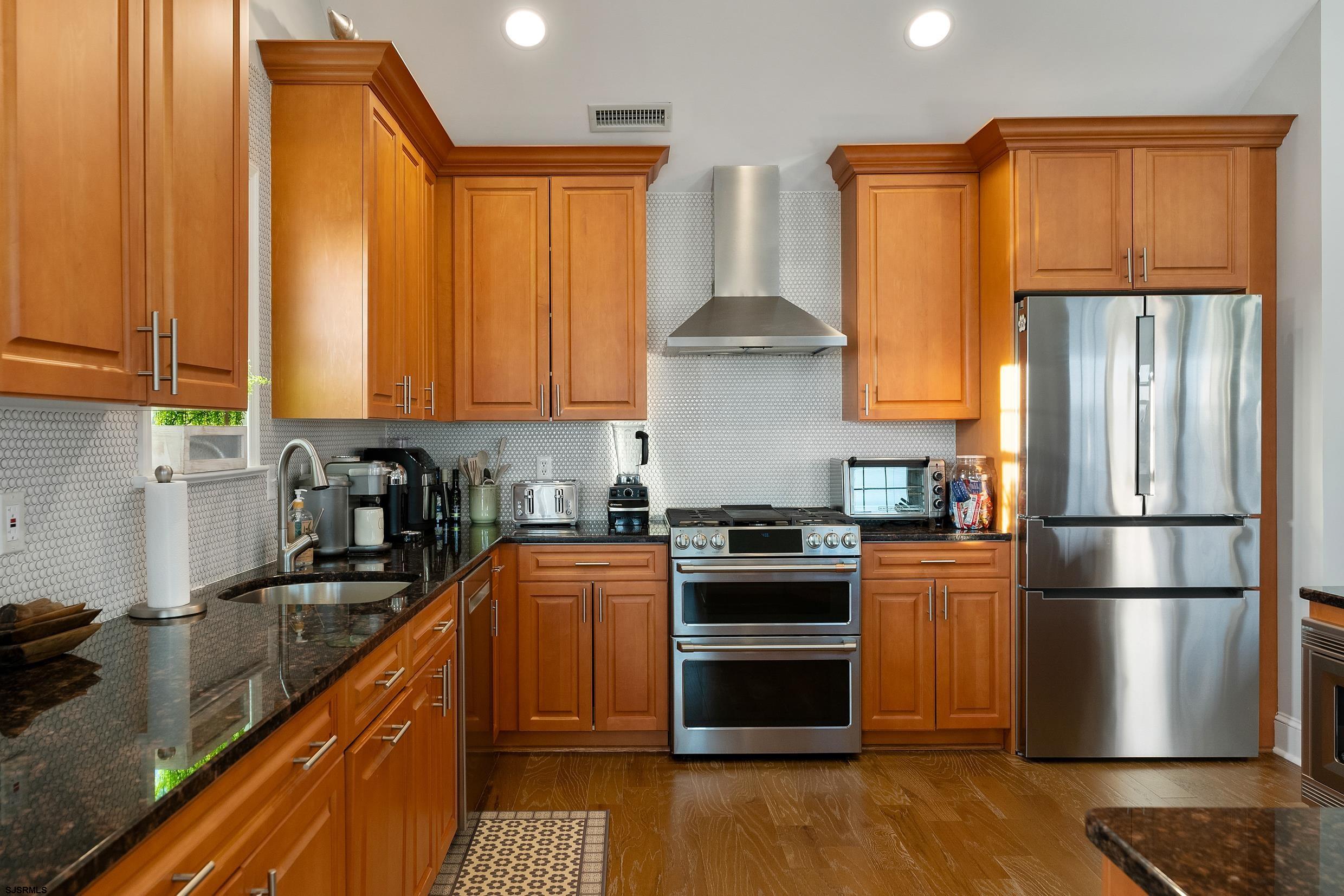 102 Broadway, Unit 2 Somers Point, NJ 08244 - Photo 22 of 98 a kitchen with granite countertop wooden floors stainless steel appliances and a sink