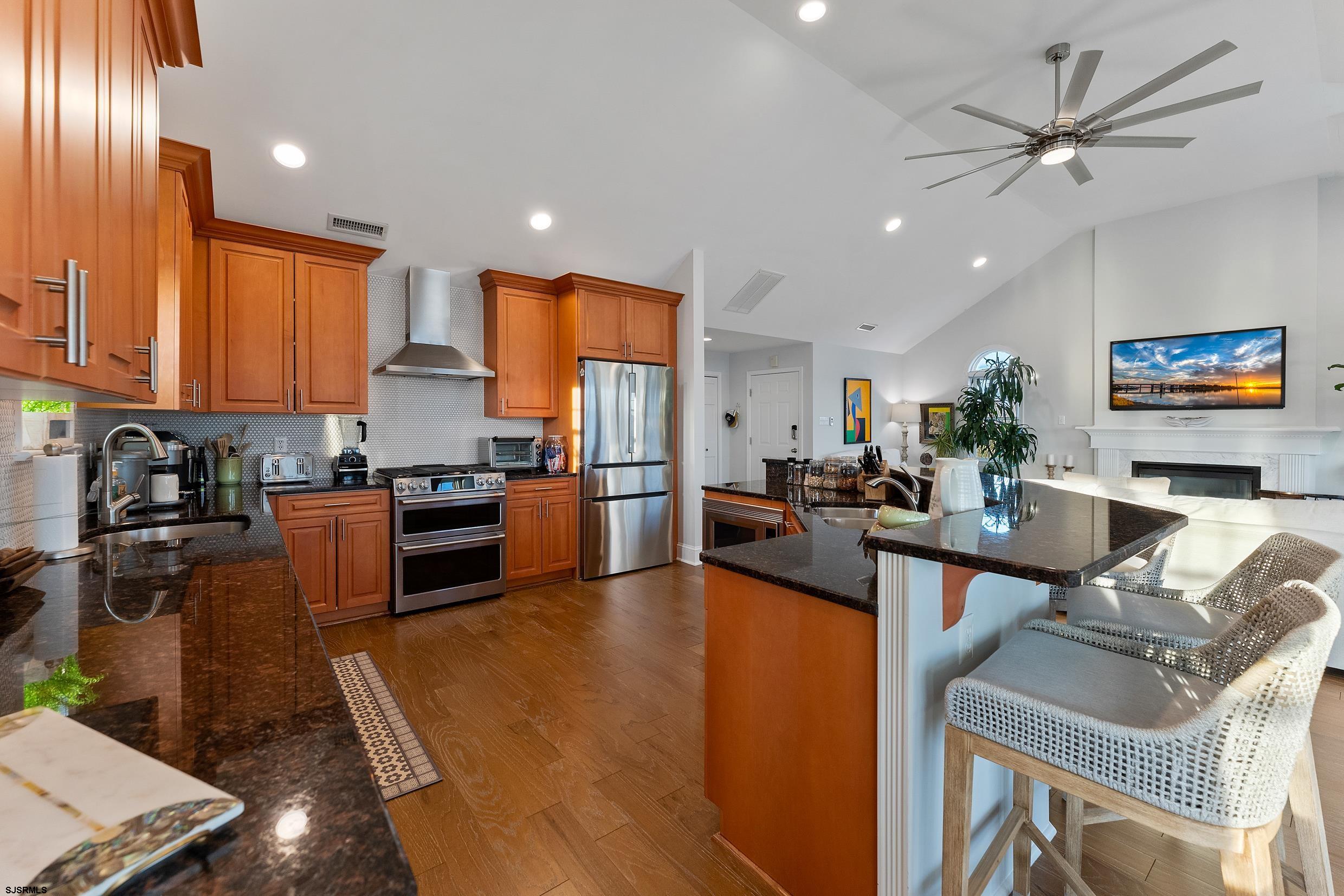 102 Broadway, Unit 2 Somers Point, NJ 08244 - Photo 23 of 98 a kitchen with stainless steel appliances granite countertop a refrigerator a stove a sink dishwasher a dining table and chairs with wooden floor