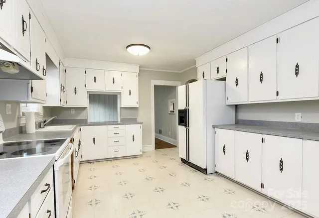 a kitchen with granite countertop white cabinets and refrigerator