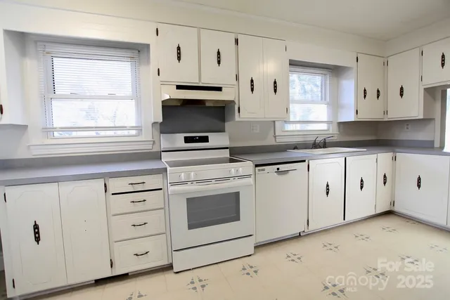 a kitchen with white cabinets appliances and a window