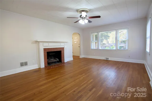 an empty room with wooden floor chandelier and fireplace