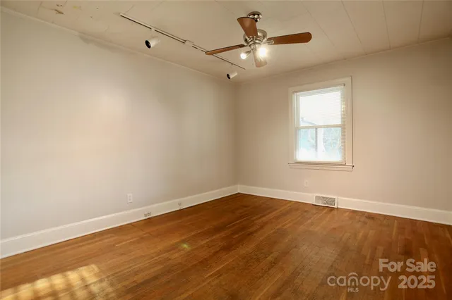 an empty room with a window and ceiling fan